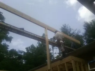 Carpenter setting a ridge beam over a new addition frame — Ice Dam Removal by Roofing Brothers in Odenton