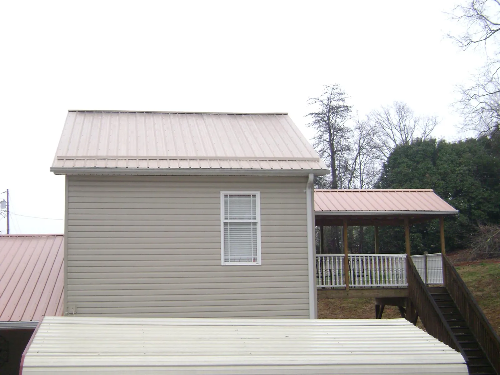 Tan metal roofs on a two story addition and attached porch, from a Roof Replacement job in Odenton