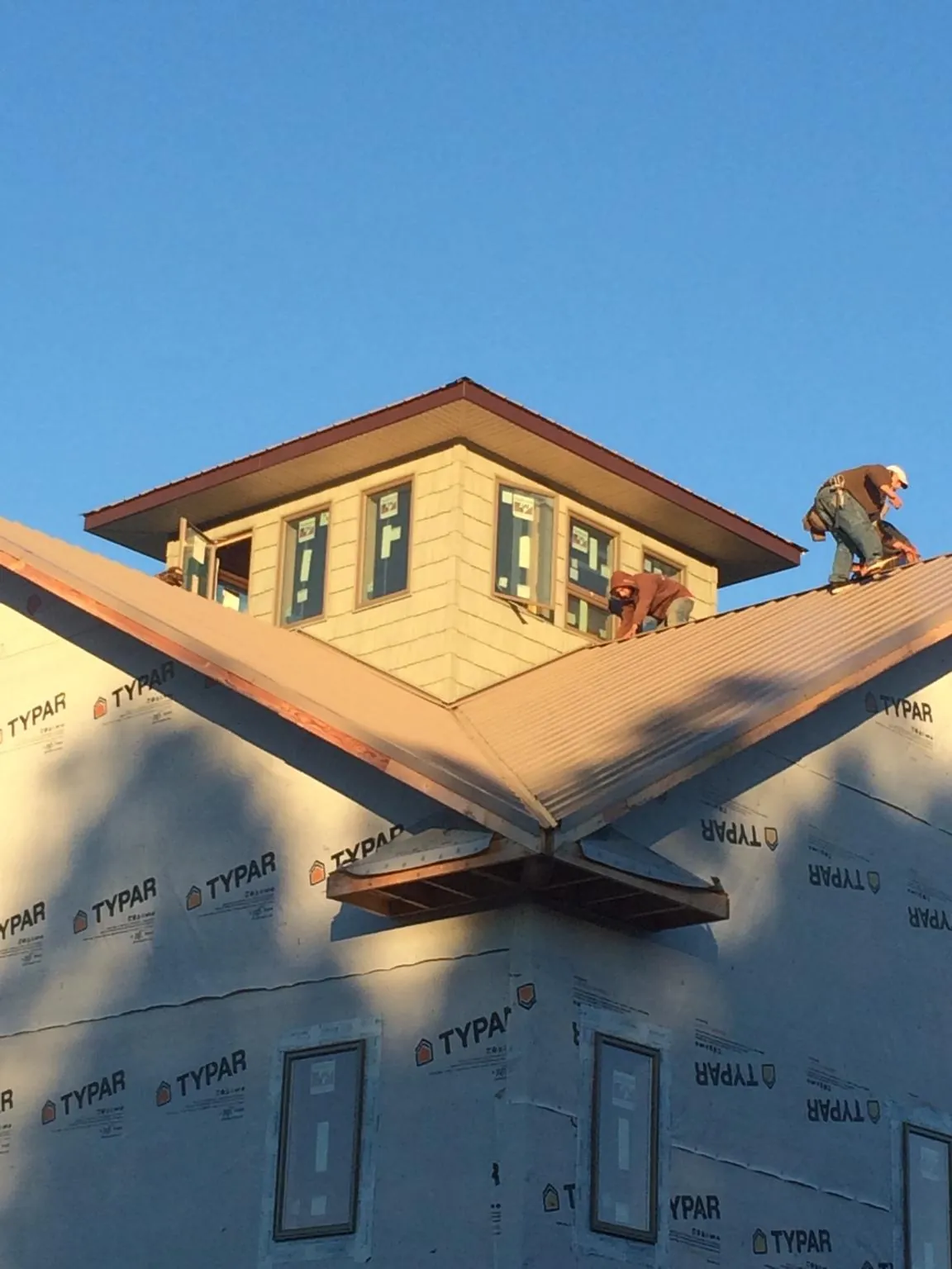 Roofers working around a rooftop cupola on a new metal roof at sunset — Roof Waterproofing in Odenton by Roofing Brothers